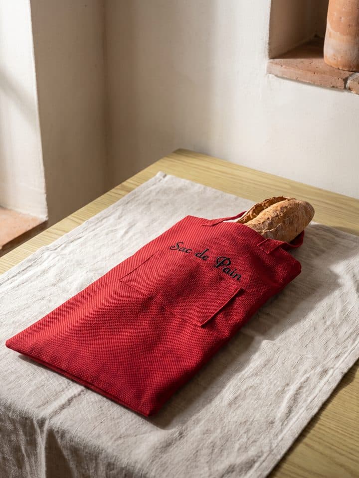 Sac de pain rouge brodé posé dans une niche murale